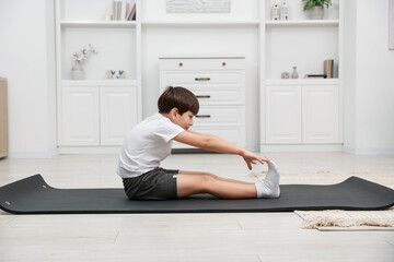 Boy doing exercise on fitness mat at home. Sport activity