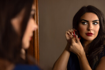 Lady in red hat putting on earrings