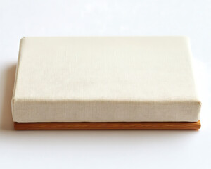 Beige cushion resting on a simple warm-toned wooden base placed on a clean white surface.