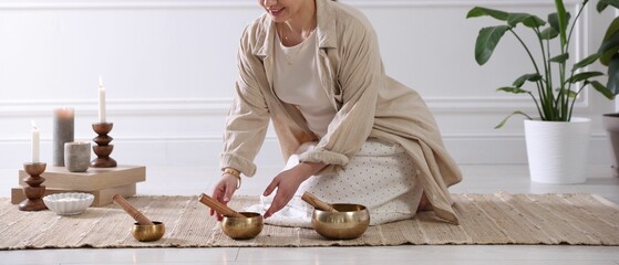 Woman with singing bowls on floor indoors, closeup