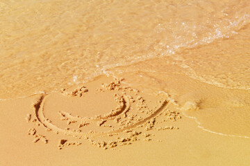 A painted smiley face on the beach sand