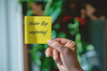 Colored paper note with masking tape with motivational phrases, hand holds a post it with blurred...