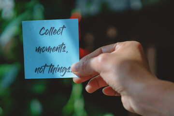 Colored paper note with masking tape with motivational phrases, hand holds a post it with blurred background, copy space.