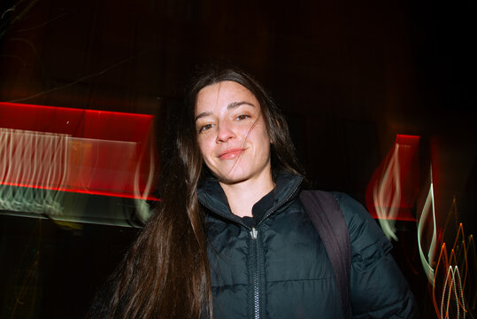 Night portrait of a woman with red light trails in the street