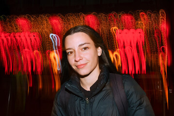 Woman posing with vibrant red light trails in background on street