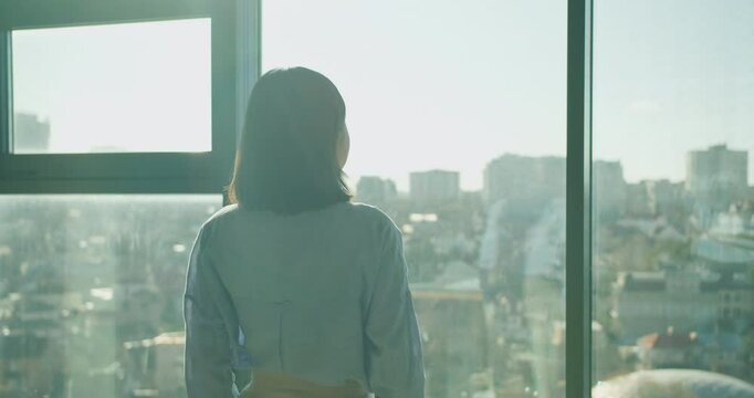 A thoughtful professional gazing out at a sprawling urban cityscape from a modern office window, symbolizing ambition, reflection, and possibilities