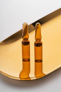 Cosmetic ampoules with anti-aging serum on golden tray