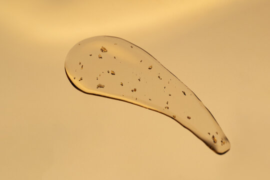 Luxurious anti-aging serum with golden flakes on golden surface