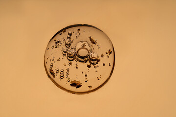 Golden particles in anti-aging face serum on clear background