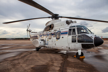 White Military Helicopter Parked on Wet Tarmac at Air Base