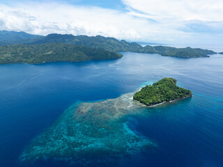 A beautiful island is surrounded by a healthy coral reef off the coast of North Sulawesi,...