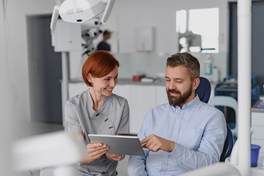 Female dentist showing x-ray to patient in dental clinic during anual check-up.