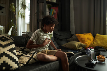 Youthful child with asthma attack keeping hand on chest and looking at inhaler with oxygen mask...