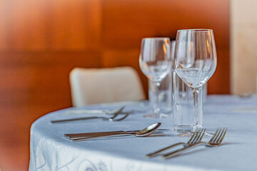 Elegant dining table arrangement featuring empty wine glasses, cutlery. For celebrations or events. Highlights simplicity, elegance, and invites a sense of hospitality.