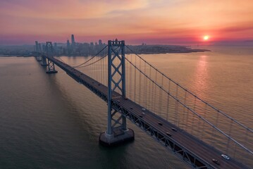 Aerial view of the Bay Bridge in San Francisco, California, USA, at sunset. Cars are driving across...