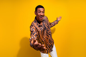 Cheerful guy in printed shirt gesturing with joy against bright yellow background, expressing...
