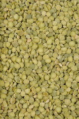 A close-up, top-down view of a pile of dried green split peas filling the frame
