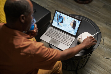 High angle of African American man with nebulizer holding mask by his face during medical treatment and online consultation