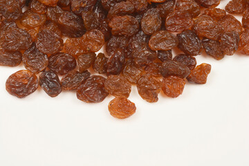 A top-down shot of a scattering of dark brown raisins on a light surface