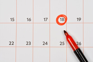 A calendar page with the date 18 circled in red, with a red marker pen pointing towards it