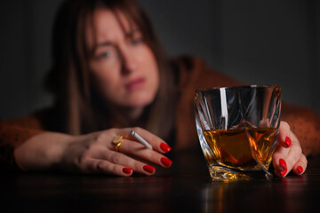 Alcohol addiction. Woman with glass of whiskey and cigarette at table indoors, selective focus