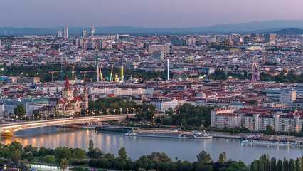 Aerial panoramic view over Vienna city with skyscrapers, historic buildings and a riverside promenade day to night timelapse in Austria.