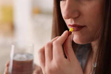 Woman taking medical pill at home, closeup