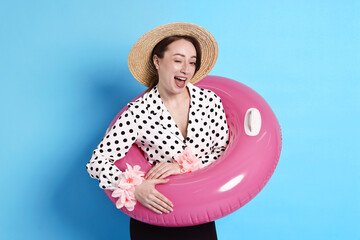 Businesswoman with inflatable ring, straw hat and flower bracelets on light blue background