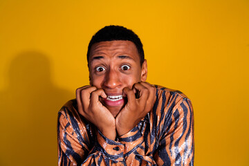 Young man in stylish tiger-print shirt looking anxious against a vibrant yellow background