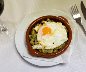 Traditional Catalan beans with a fried egg. Delicious Spanish dish Habitas catalana with bacon and sausages