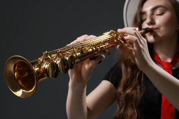 Musician playing soprano saxophone on grey background