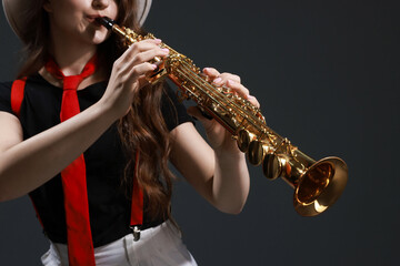 Musician playing soprano saxophone on grey background
