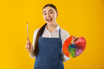 Fototapeta premium Happy woman with palette and paintbrush on orange background