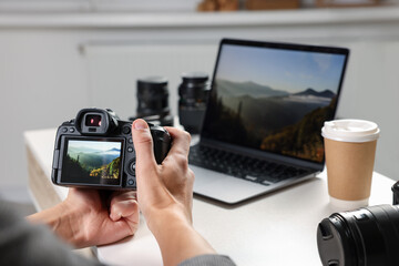 Photographer with professional camera at white desk indoors, closeup