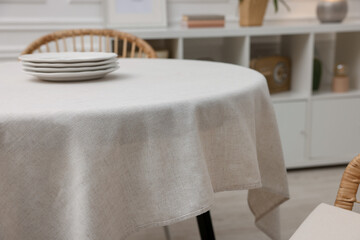 Table with white tablecloth and plates in room, closeup