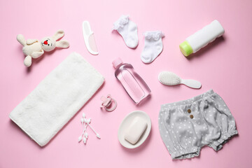 Baby oil, clothes and bath accessories on light pink background, flat lay