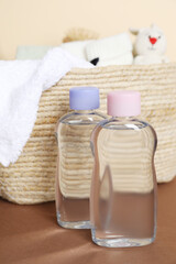 Baby oil and bath accessories in basket on color background, closeup