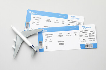 Travel agency. Flight tickets and plane model on grey background, flat lay