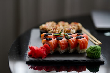 Sushi set on a black background. Sushi roll with salmon, caviar, cream cheese and wasabi.