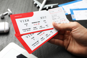 Travel agency. Man with flight tickets at dark textured table, closeup