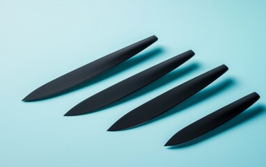Obraz premium Sleek black kitchen knives arranged on a light blue surface for culinary preparation and presentation