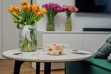 A patterned cup on a living room table with flowers
