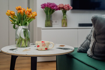 A patterned cup on a living room table with flowers