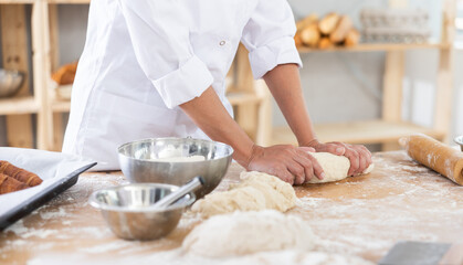Female baker rolling out raw dough close-up