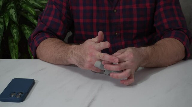a man removes a splint from his finger after recovery. a medical locking device that provides the finger with an inflexible position.