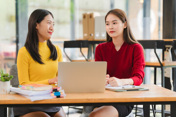 Fototapeta premium Two Young Women Collaborating at Desk