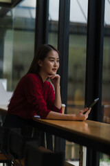 Obraz premium Thoughtful Woman with Tablet by Window