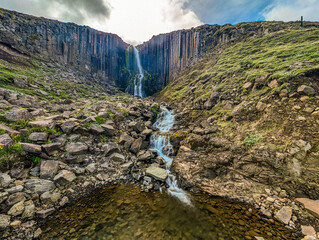 A scenic view of Studlagil Canyon in Iceland with basalt columns and a turquoise river.
