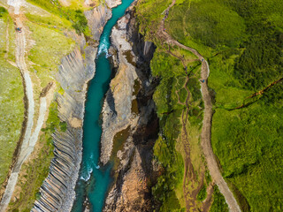 A scenic view of Studlagil Canyon in Iceland with basalt columns and a turquoise river.