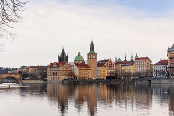 Obraz premium Vltava river reflecting colorful buildings and Old Town Bridge Tower in Prague